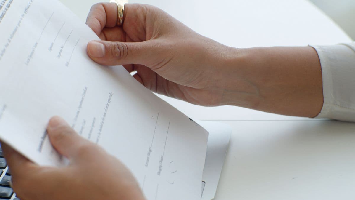 Two hands holding a printed application form.